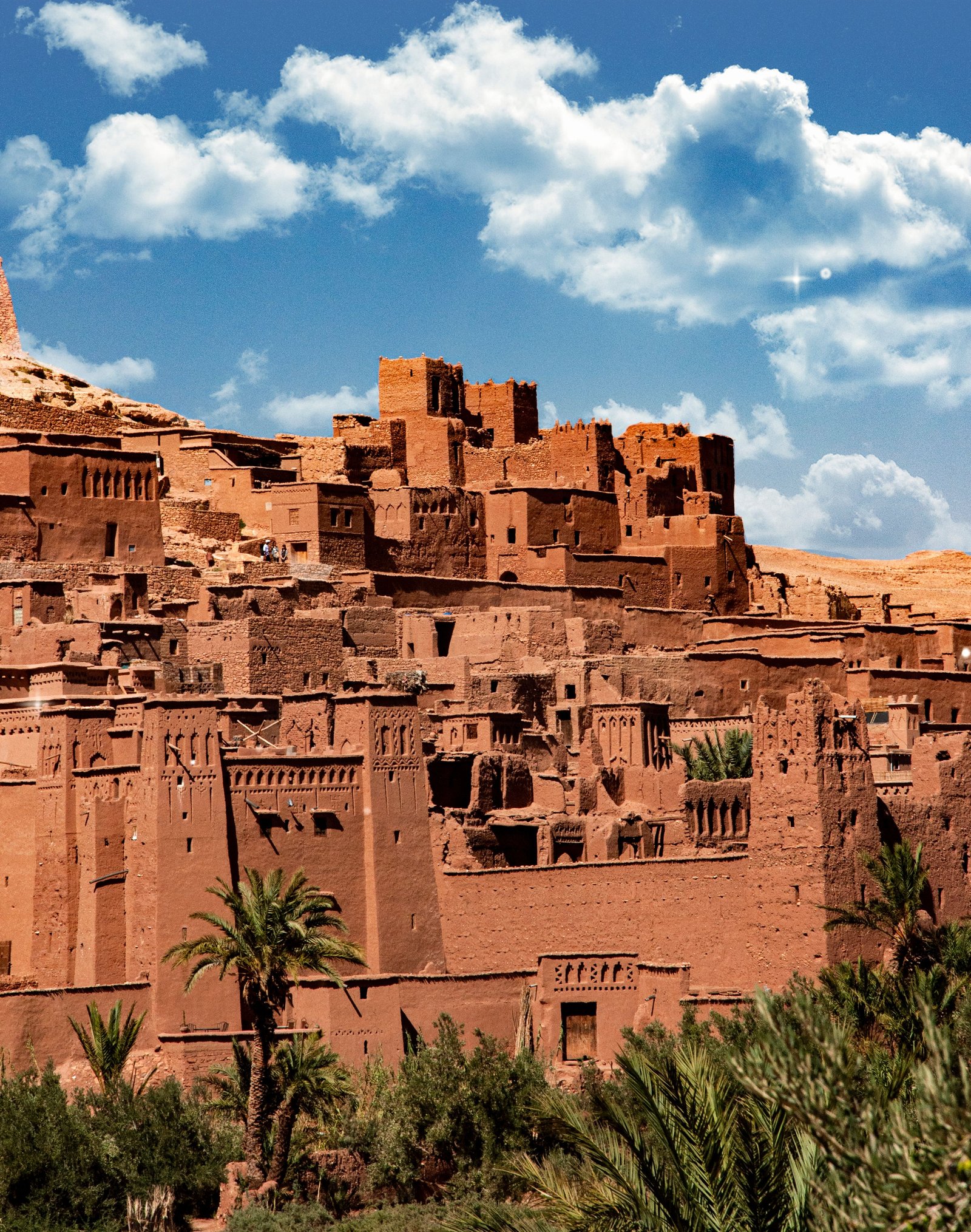 historic Ait Ben Haddou kasbah on a hillside with mud brick towers and surrounding palm trees